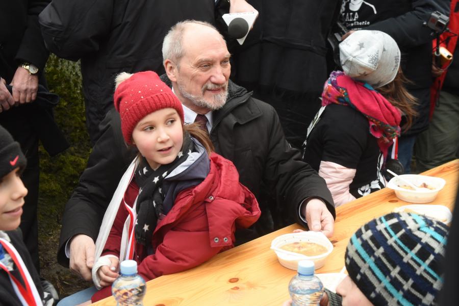 Minister obrony narodowej Antoni Macierewicz siedzi przy stole z najmłodszymi uczestnikami biegu - dla wszystkich chętnych kuchnia polowa przygotowała gorącą grochówkę.